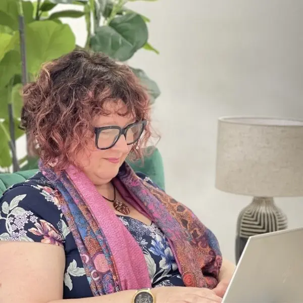Celia at her desk, working on a project, using her latop