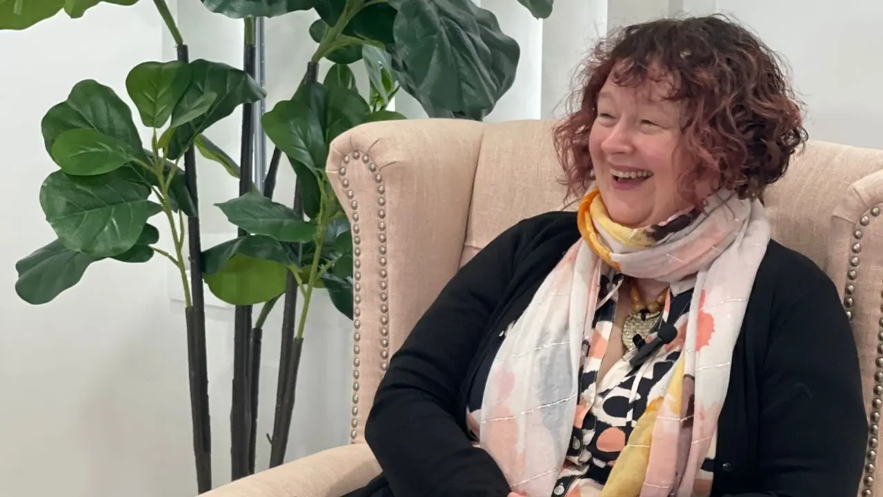 Celia Newlands smiling, whilst sitting in a comfy lounge chair